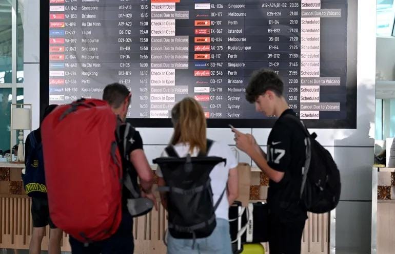 Passengers look at an electronic board displaying cancelled flights at Ngurah Rai airport on June 18, 2025